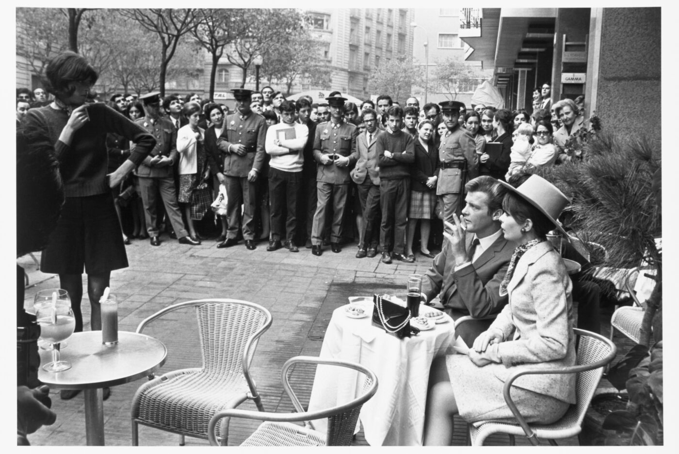 Photographic Social Vision - Seguidores de  Roger Moore «El santo» observan al  actor mientras se toma un vermut.  Barcelona, 1967.