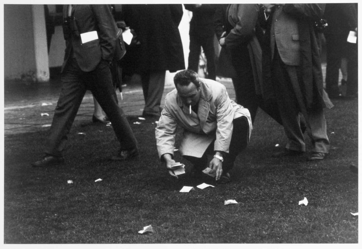 Photographic Social Vision - Un hombre recoge boletos con posibilidad de premio.  Hipódromo de La Zarzuela. Madrid, 1967.