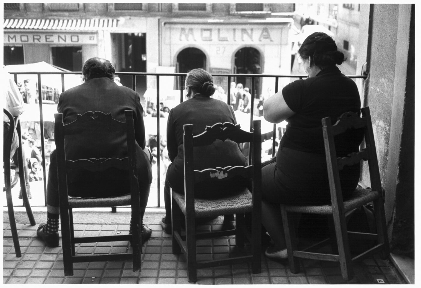 Photographic Social Vision - Un hombre y dos mujeres observan un desfile desde su balcón. Málaga, 1975.